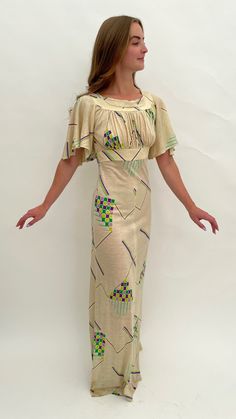 "This 1970s maxi dress is very much influenced by 1930s design and style with its repeating Art Deco geometric design and pretty, fluttery sleeves. The main colour is cream with the highlight colours in shades of green, lilac and purple. The fabric is acrylic which has a slight stretch. It is labelled inside 'Tina Warren Made in England'. There is a zip to the back and a hook and eye fastening.  The inside size label says '36' but this is an old size so please go by all the measurements here to see if it will fit you. When laid flat and fastened the measurements are: Length: 61\" inches Across the waist: 14\" inches Across the hips: 17\" inches From underarm to underarm across: 16\" inches Across the band under the bust: 13.5\" inches  It is in good overall condition with the following age Vintage Beige Short Sleeve Maxi Dress, Beige Short Sleeve Vintage Maxi Dress, Beige Vintage Short Sleeve Maxi Dress, Beige Vintage Maxi Dress With Short Sleeves, 1930s Design, Lace Handkerchief, 1970s Dress, 1970s Style, Art Deco Geometric