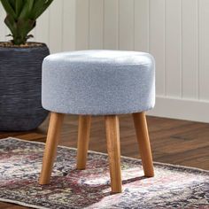 a small stool with wooden legs and a blue upholstered seat on top of a rug