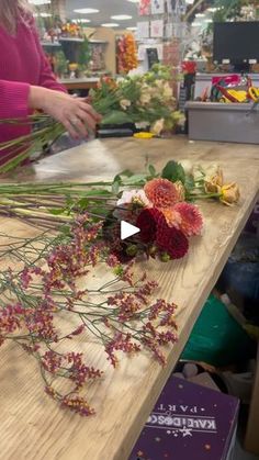 a woman arranging flowers on a table in a flower shop