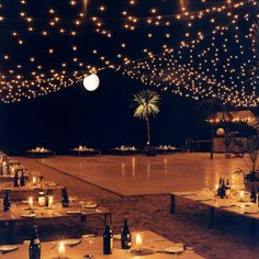 an outdoor dining area is lit up with string lights