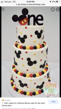 a three tiered cake decorated with mickey mouse ears and the word one on top