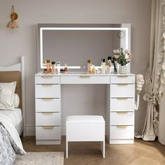 a white dressing table with drawers and a mirror on it in a bedroom next to a bed