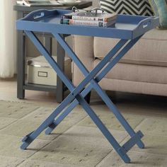 a blue tray with some books on it in front of a couch and coffee table