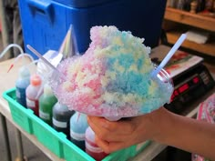 a person holding an ice cream sundae in their hand with other items behind it