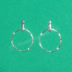 two small silver hoop earrings on a green background with the word, it was made from metal