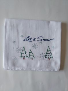 a white napkin with christmas trees and let it snow written on it