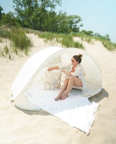 a woman sitting in a tent on the beach