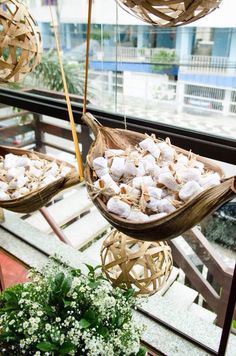 two baskets filled with marshmallows on top of a wooden table next to a potted plant