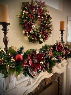 a fireplace mantel decorated for christmas with wreath and poinsettis on it