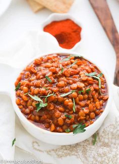 a white bowl filled with baked beans and garnished with herbs