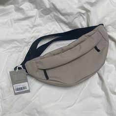 a gray fanny bag sitting on top of a white sheet with a tag attached to it