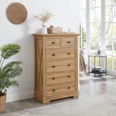 a wooden dresser sitting next to a window in a room with a potted plant