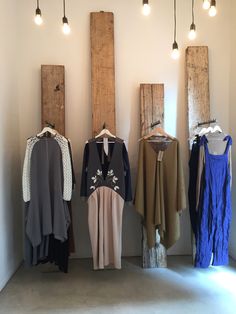 clothes are hanging on the wall in front of some wooden planks and light bulbs