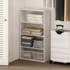 a white suitcase sitting next to a shelf with folded towels and other items on it