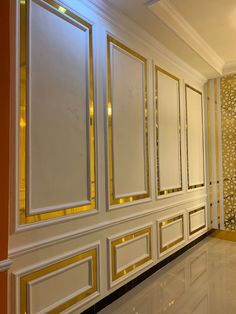 an empty room with white and gold decor on the walls, along with marble flooring