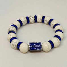 a white and blue beaded bracelet with a name tag that reads finex on it