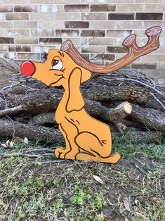 a wooden toy dog sitting in front of a pile of wood logs with a red nose