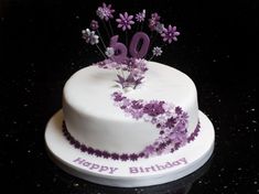 a white birthday cake with purple flowers on top