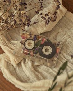 an old cd sitting on top of a table next to dried flowers