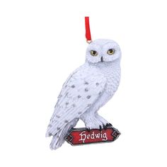 a white owl ornament hanging from a red ribbon with the words bedwig on it