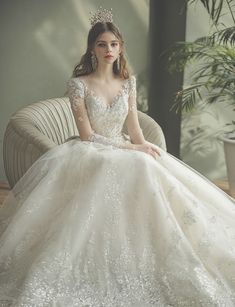 a woman in a wedding dress sitting on a chair wearing a tiara and earrings