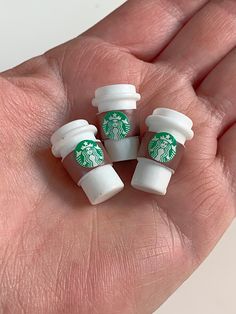 four starbucks cups sitting in the palm of someone's hand