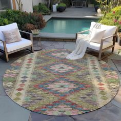 an outdoor area with two chairs and a rug on the ground next to a pool