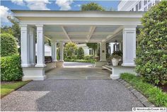 an outdoor covered walkway leading to a building with columns and pillars on each side, surrounded by greenery