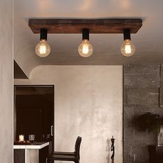 three light bulbs are hanging from the ceiling above a dining room table with chairs and stools