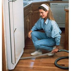 a woman vacuuming the floor in her kitchen with a hose attached to the door