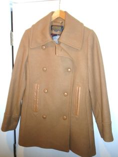 Pendleton Wool Blend Camel Tan Double Breasted Peacoat two lower hand-warmer pocket with leather trim 80% Wool / 20% Nylon Coat is fully lined Color: listed on the tag as Camel Tan Double Breasted with leather buttons front Closure includes extra buttons Size: Size 10  shoulder to shoulder measures 16 inches straight across armpit to armpit measures 21 inches straight across jacket is 30 inches long (measured from the back of the neck) sleeve measures 25 inches (from the shoulder seam to the cuf Cottage Closet, Pendleton Wool, Leather Trim, Hand Warmers, Leather Trims, Vest Jacket, Double Breasted, Wool Blend, Size 10