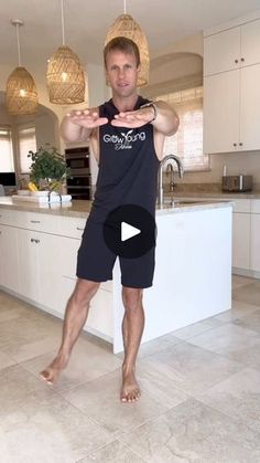 a man standing in front of a kitchen counter pointing at the camera with his hand