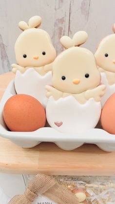 three little chicks in an egg carton on a table with two eggs and one orange