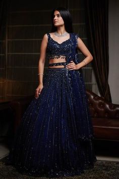 Navy blue lehenga with attached cancan, highlighted with sequin-cutdana and resham embroidery. Comes with cutwork V-neckline padded blouse, dupatta and belt.
Components:4
Embroidered
Neckline:V-Neck
Sleeve Length:Sleeveless
Fabric:Net
Color:Blue
Embroidered blouse with cutwork hem
Beaded tassels
Low back neck with tie-up
Embroidered scallop edged dupatta and belt - Aza Fashions Lahenga Design For Reception, Royal Blue Velvet Lehenga, Navy Blue Lehenga, Lehenga Online Shopping, Gown Dress Party Wear, Indian Dress Up, Bridal Lehenga Online, Reception Bride, Sangeet Outfit