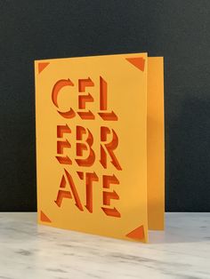 an orange greeting card with the words cel febr ate printed in red on it