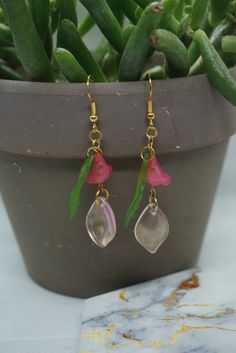 pink glass beads of a flower green leaf and pink petal Handmade Pink Teardrop Flower Earrings, Pink Dangle Flower Charm Earrings, Pink Flower Beaded Earrings For Gift, Bohemian Pink Earrings With Flower Charm, Pink Flower Glass Jewelry, Pink Bohemian Resin Jewelry, Pink Flower-shaped Glass Jewelry, Bohemian Pink Resin Jewelry, Pink Bohemian Flower Earrings