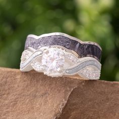 a wedding band with a diamond in the center on top of a rock