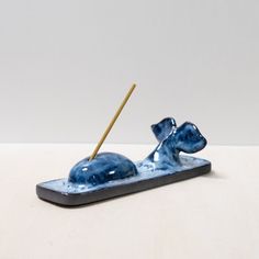 a small blue dog figurine with a stick in it's mouth