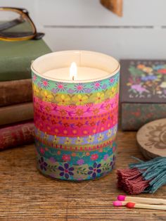 a colorful candle sitting on top of a wooden table next to books and other items