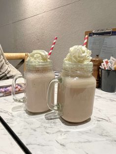 two mugs filled with whipped cream on top of a counter