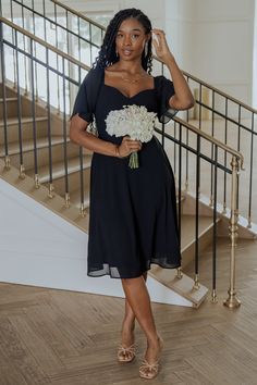 a woman in a black dress is standing on the stairs