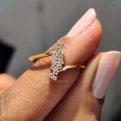 a woman's hand holding a gold ring with three diamonds on it and the middle finger