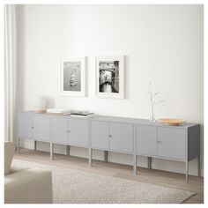 a white room with two pictures on the wall and a gray sideboard in front of it