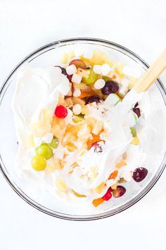 a glass bowl filled with fruit salad and sour cream toppings on top of it