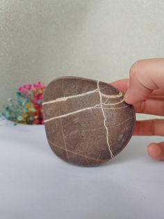 a hand is holding a rock that looks like it has been painted with white paint