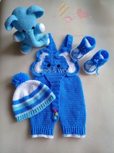 two knitted baby items are laying next to each other on a table with an elephant toy