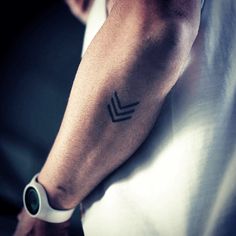 a man's arm with a small arrow tattoo on the left side of his arm