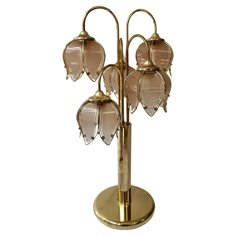 a gold colored lamp with five glass flowers on it's base and four lights attached to the top