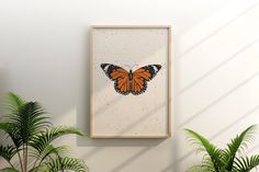 an orange butterfly sitting on top of a white wall next to potted plants and a plant