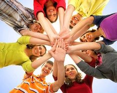 a group of people standing in a circle with their hands on top of each other